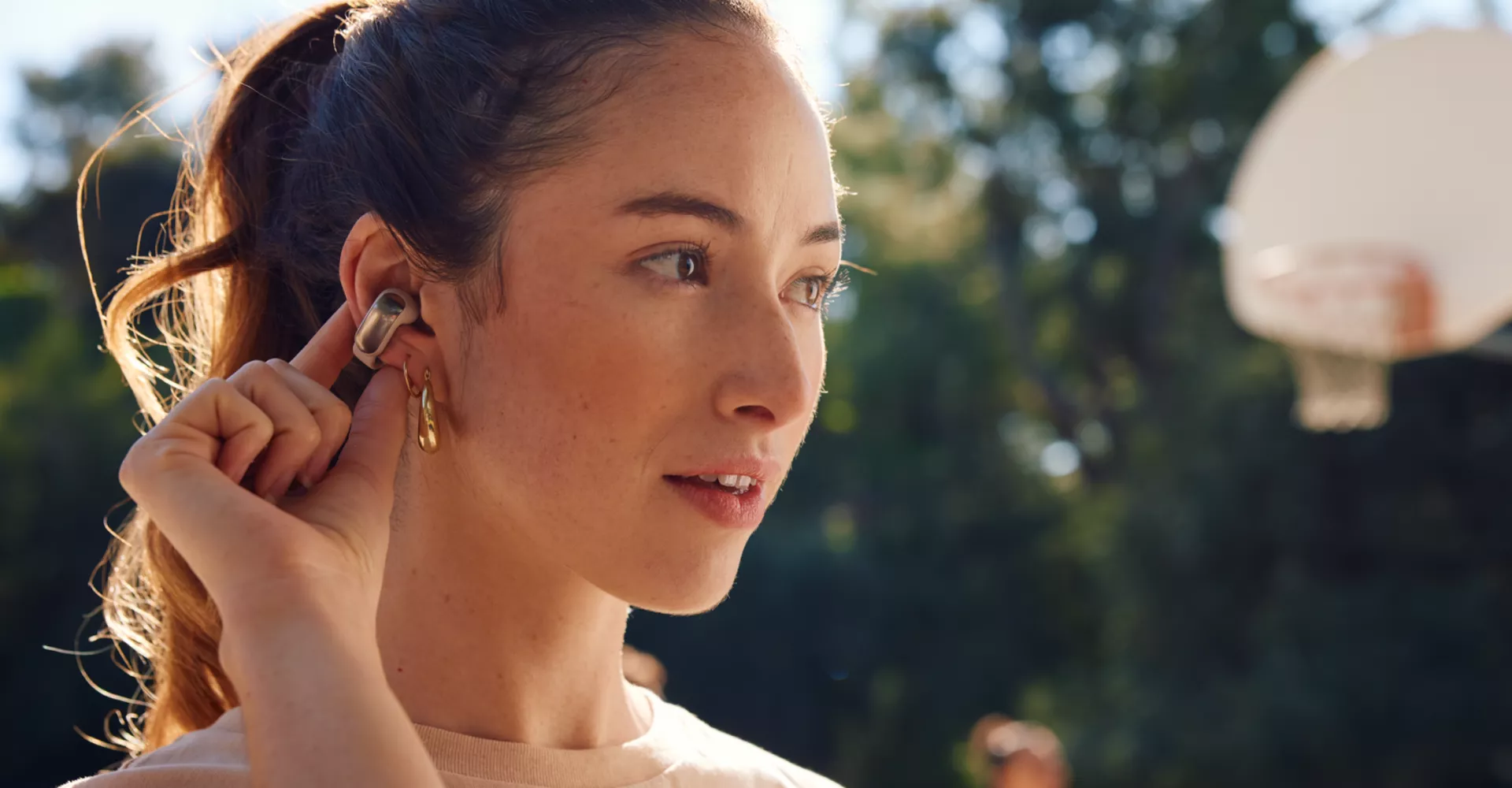 Woman using the touch controls of the Bose Ultra Open Earbuds