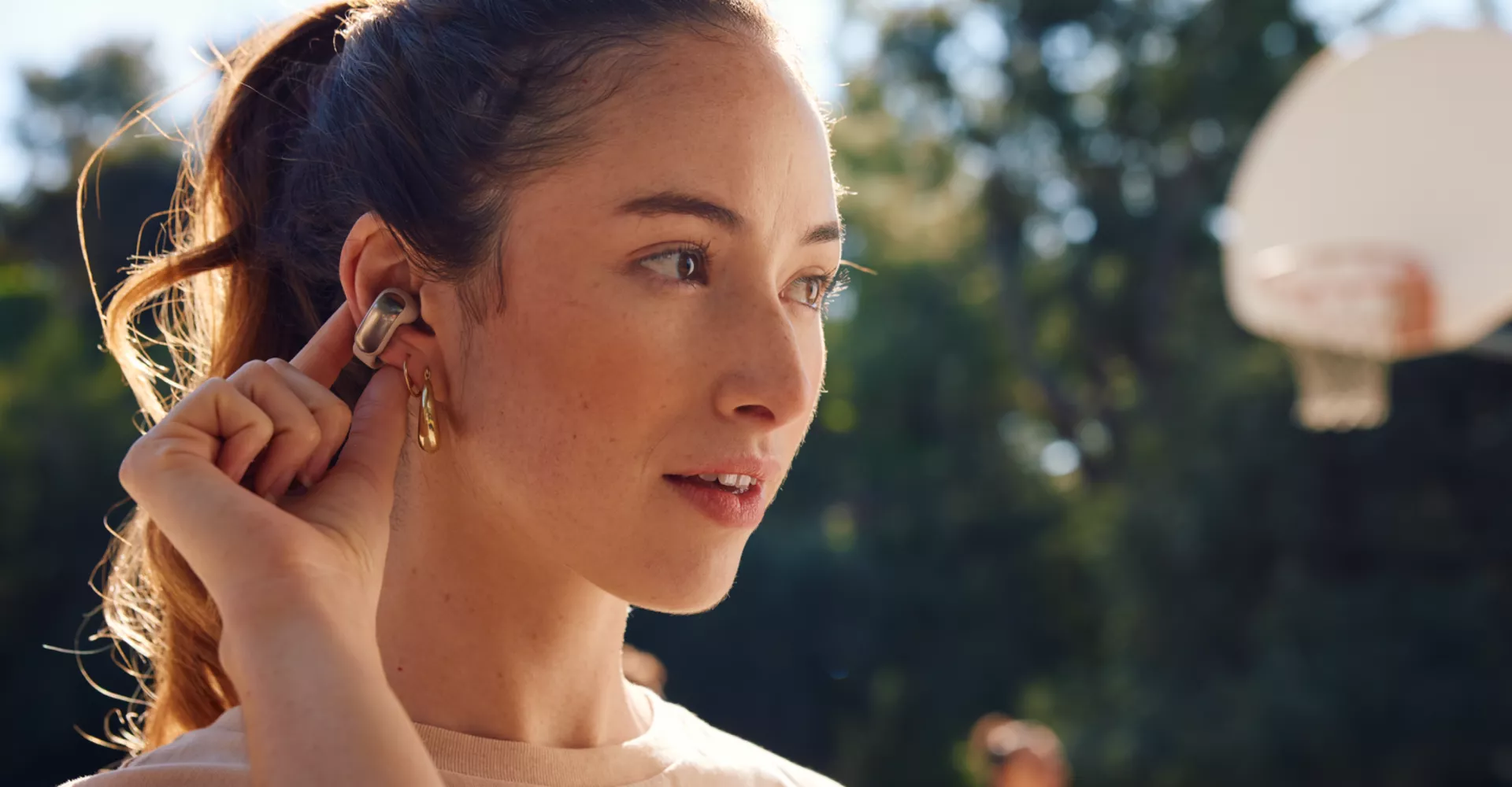 Femme utilisant les commandes tactiles des écouteurs oreilles libres Bose Ultra