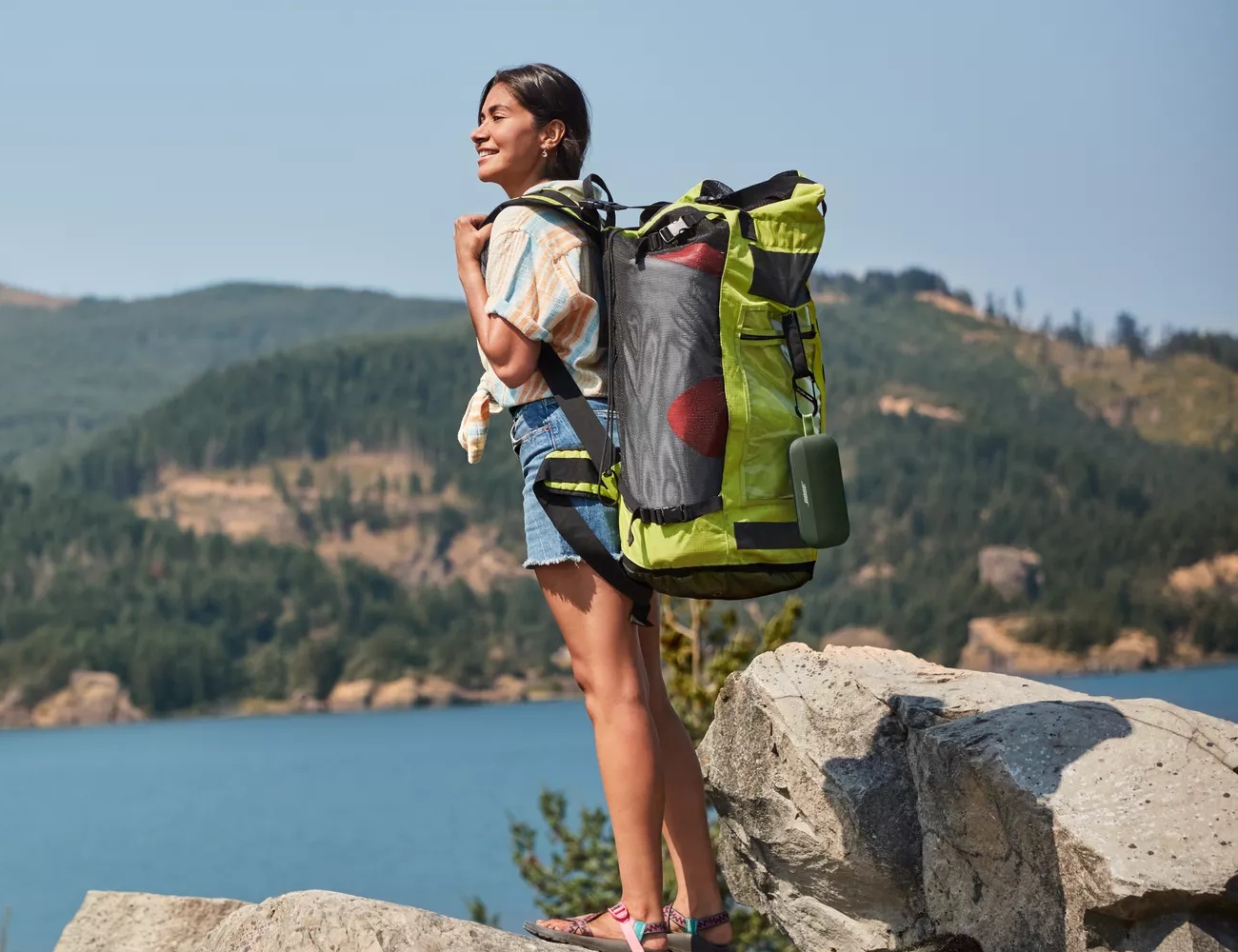 A woman hiking with a Bose SoundLink Flex attached to her backpack