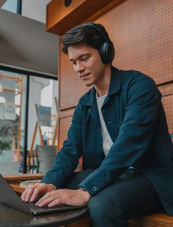 Man wearing QuietComfort 45 Headphones while working remotely on his laptop