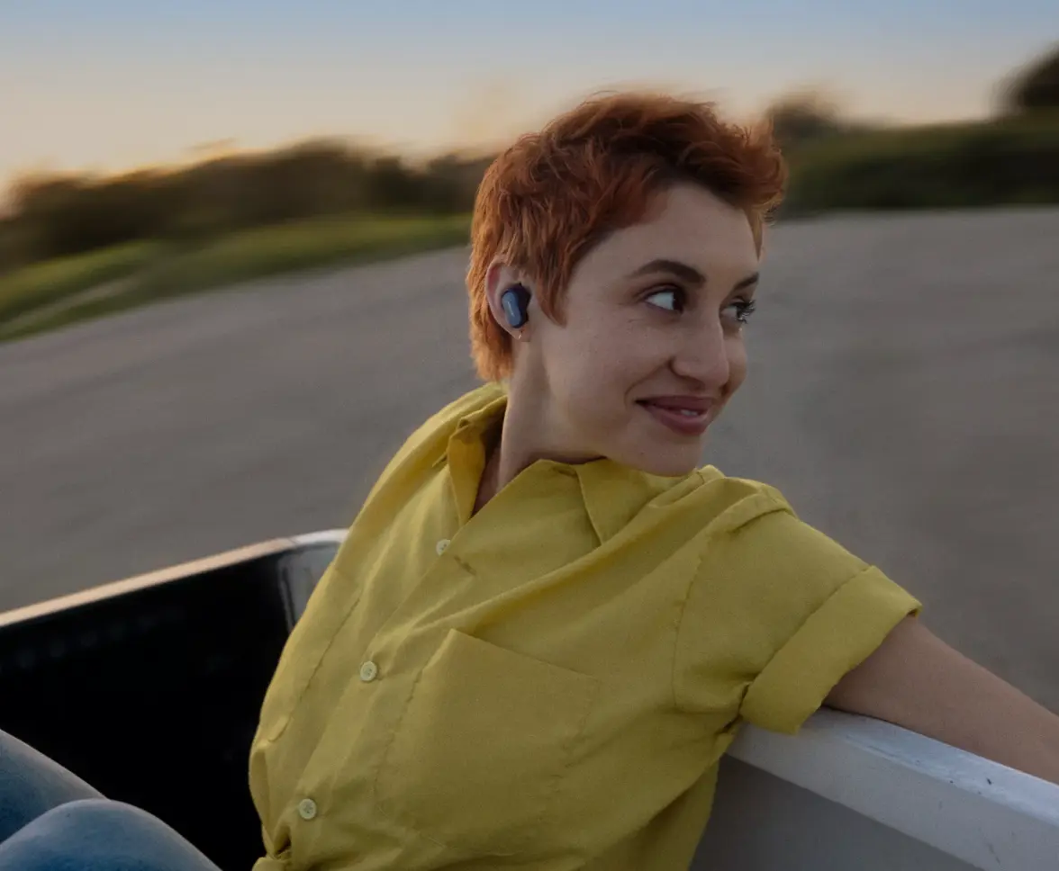 Woman wearing Bose QuietComfort Earbuds II riding in the back of a pickup truck