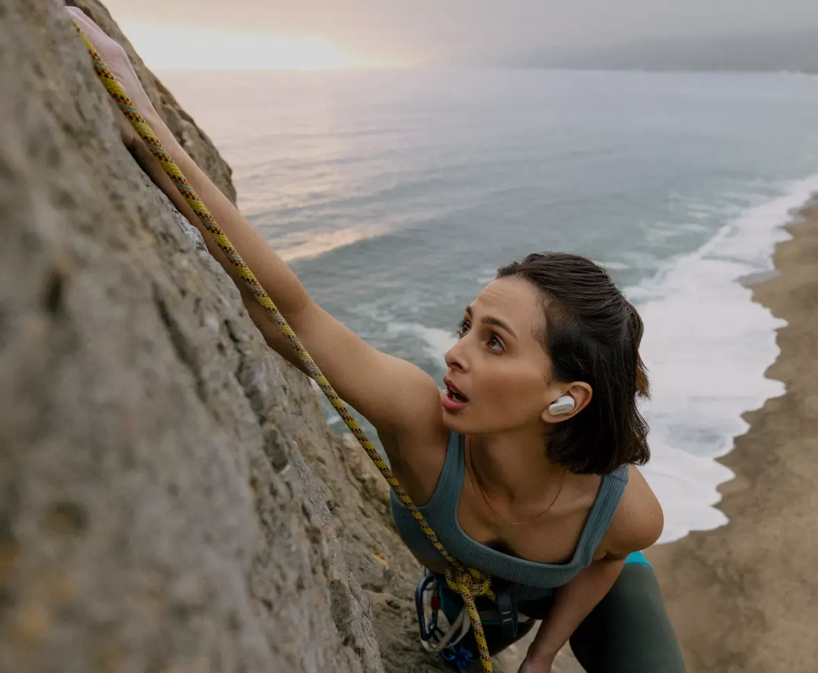 Woman rock climbing with earbuds in