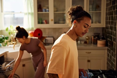 Man wearing Bose Ultra Open Earbuds while cleaning the kitchen with his wife