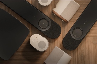 Bose Lifestyle Ultra Soundbar, Lifestyle Ultra Speakers, and Lifestyle Ultra Subwoofer home audio system in Nue Black and Driftwood Sand arranged on a wooden floor.