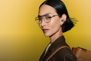 Woman wearing Bose Ultra Open Earbuds (2nd Gen) while wearing glasses and earrings.