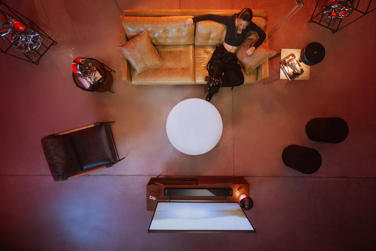 Aerial view of a woman sitting on couch and watching movie with a Bose Smart Ultra Soundbar