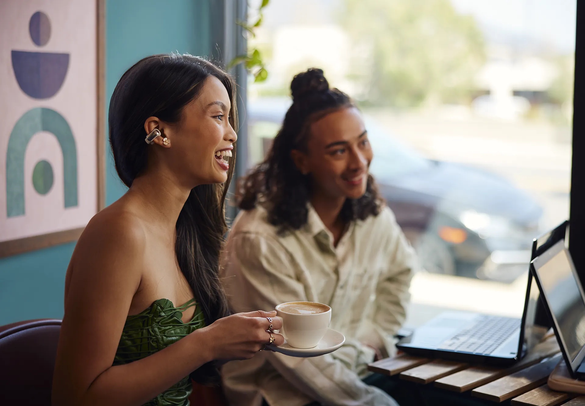 Friends meeting in a cafe wearing Bose Ultra Open Earbuds.