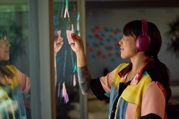 Woman wearing Bose QuietComfort Ultra Headphones (1st Gen) while posting sticky notes on a board.