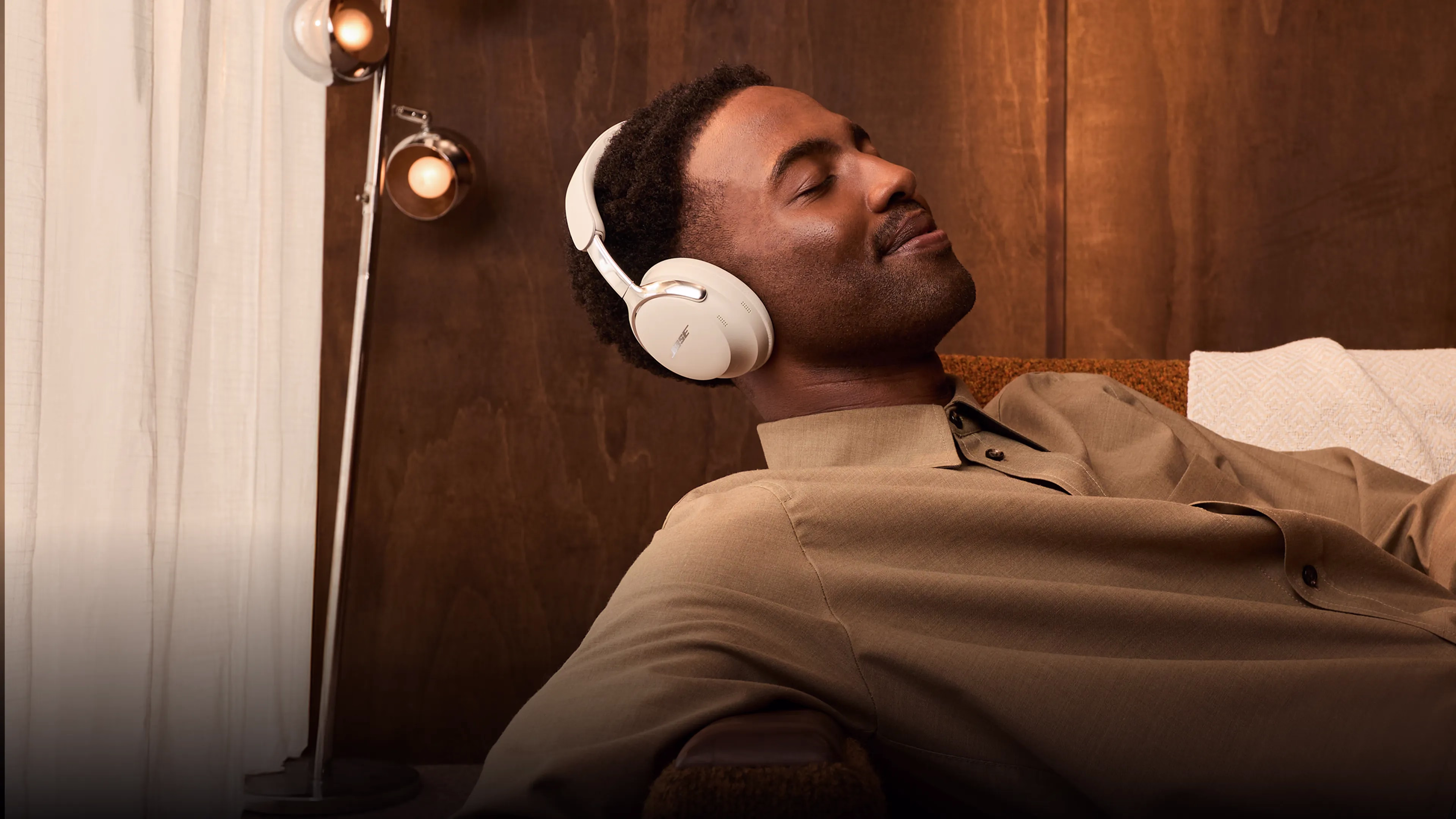 A dad relaxing on a couch with his eyes closed wearing Bose QuietComfort Ultra Headphones (2nd Gen).