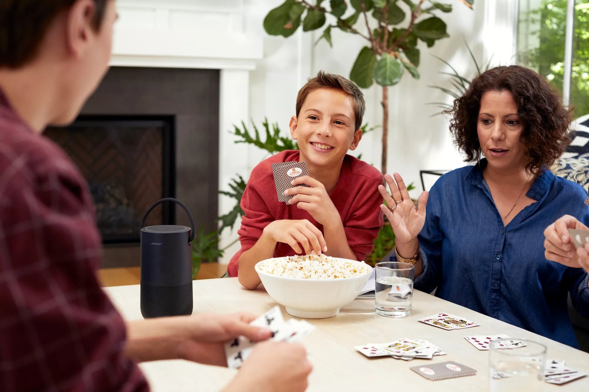 Famille heureuse à table profitant d’une enceinte intelligente portative Bose