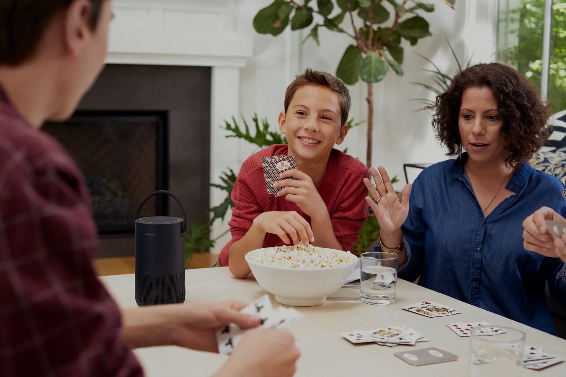 Famille heureuse à table profitant d’une enceinte intelligente portative Bose