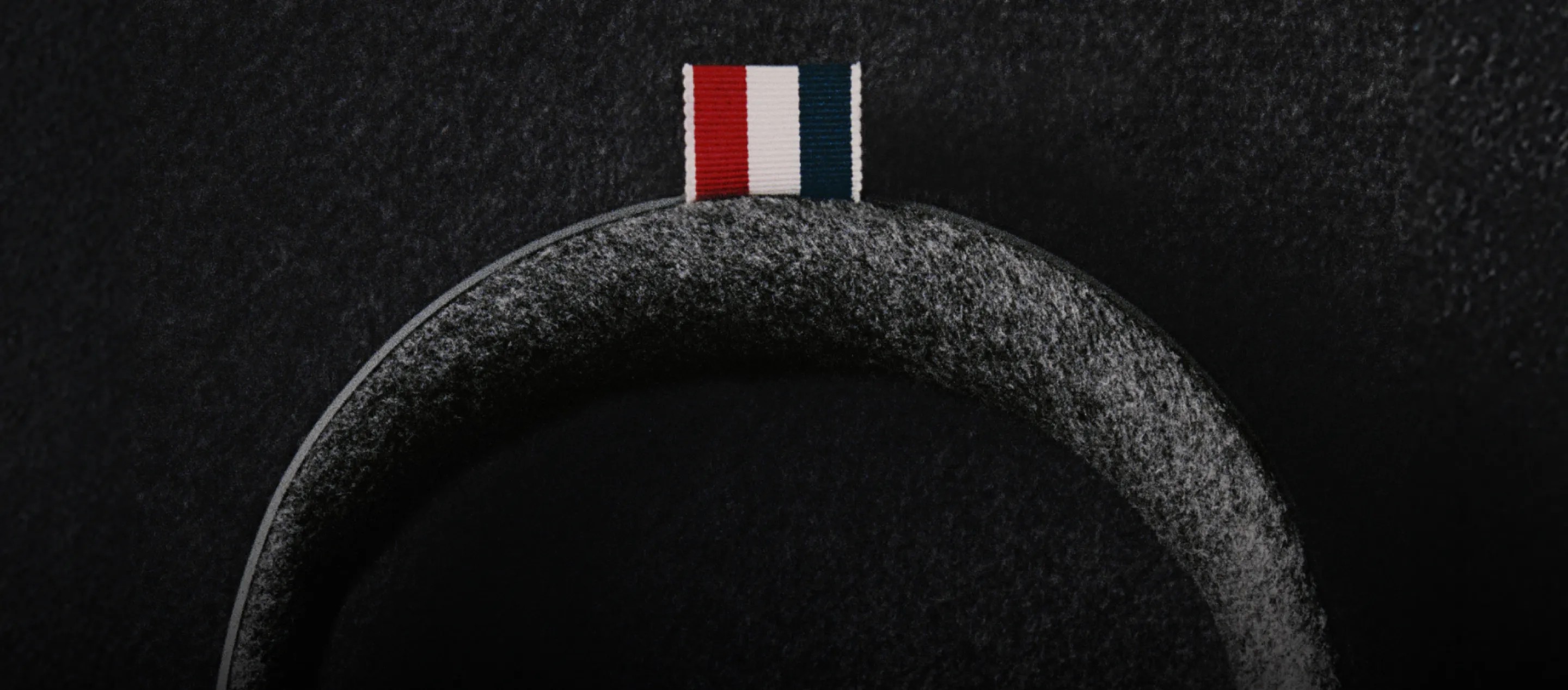 Close-up of the red, white and blue grosgrain tab on the Bose x Thom Browne headphones headband