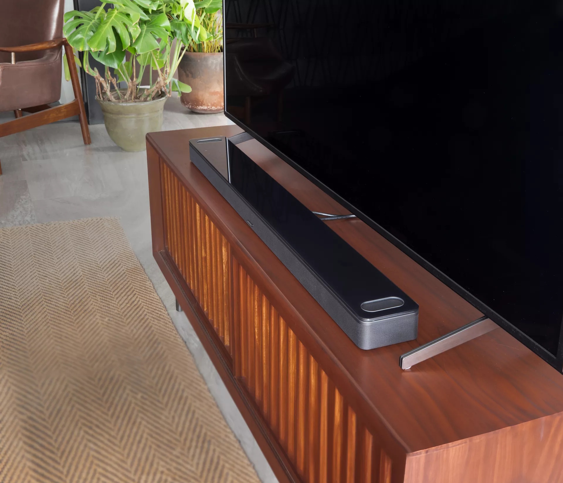 Bose Smart Soundbar 900 on TV stand in front of a television