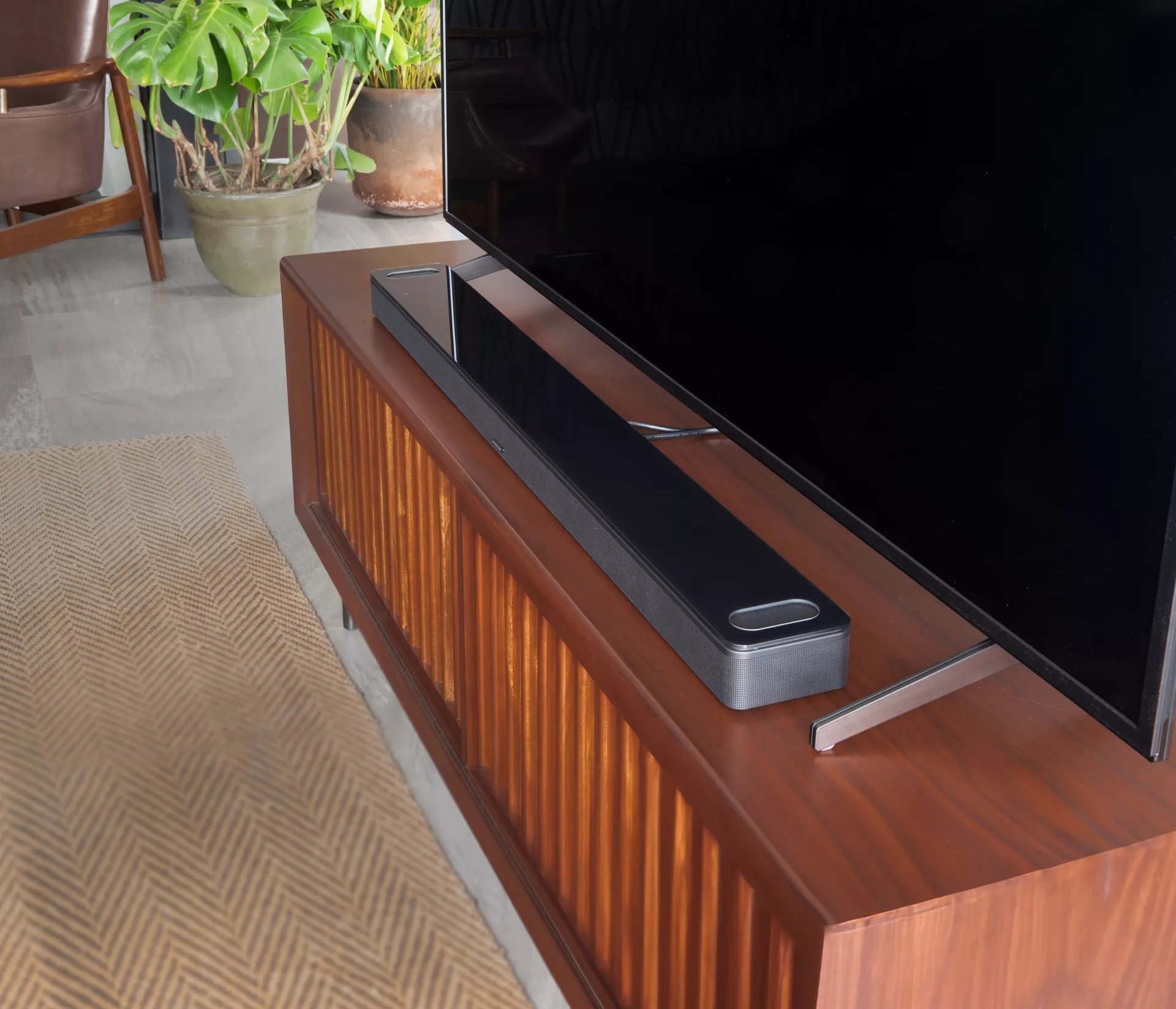 Bose Smart Soundbar 900 on TV stand in front of a television