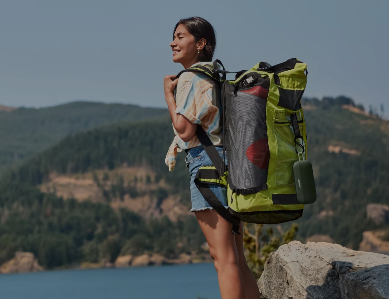 A woman hiking with a Bose SoundLink Flex attached to her backpack