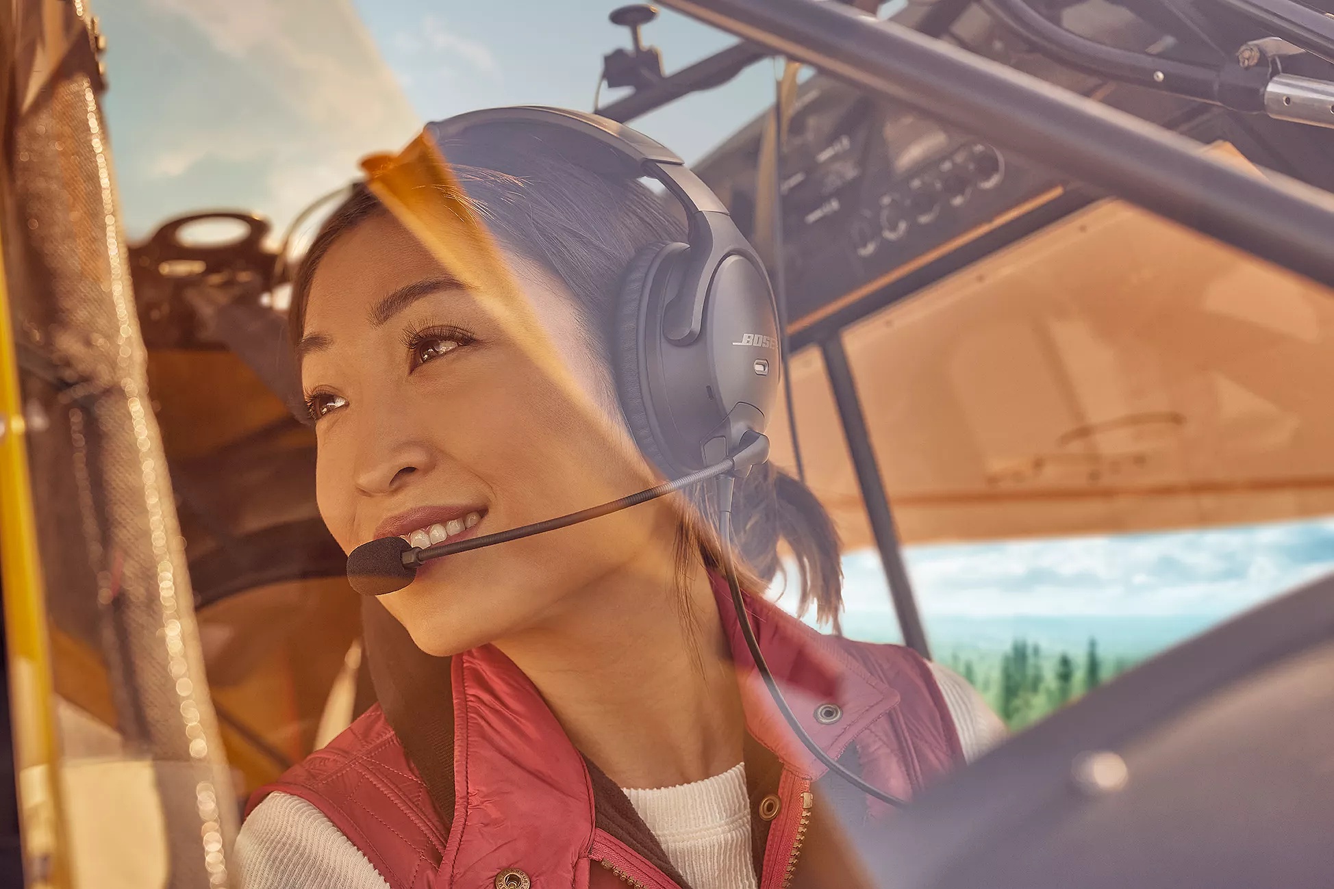 Female pilot wearing the Bose A30 Aviation Headset and looking over her shoulder at the view outside the cockpit