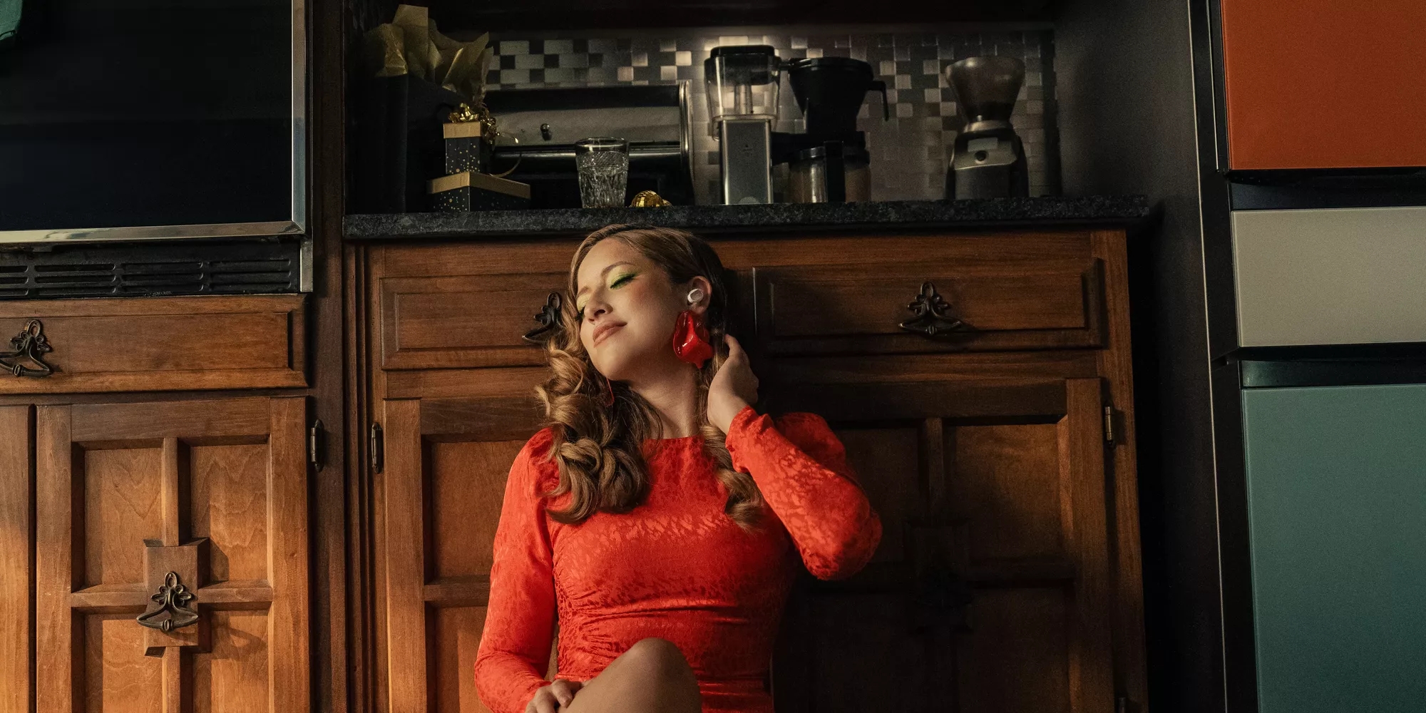 Femme dans une cuisine après un rassemblement des Fêtes et écoutant de la musique depuis des écouteurs Bose QuietComfort Ultra