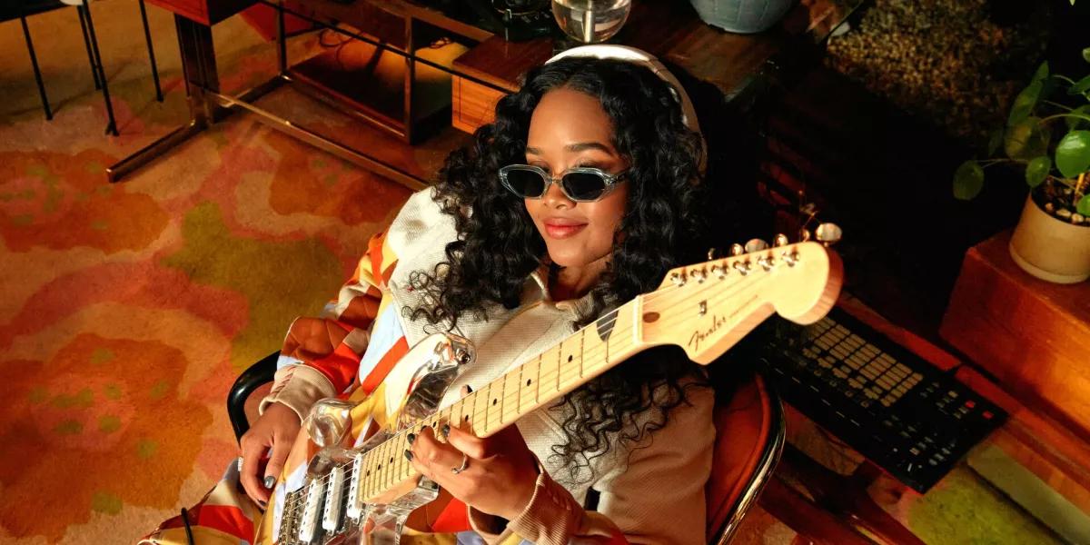 H.E.R. holding a guitar