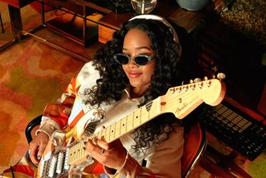 H.E.R. holding a guitar