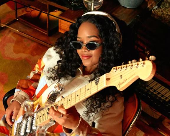 H.E.R. holding a guitar