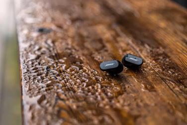 Bose QuietComfort Earbuds II on a wet bench outside