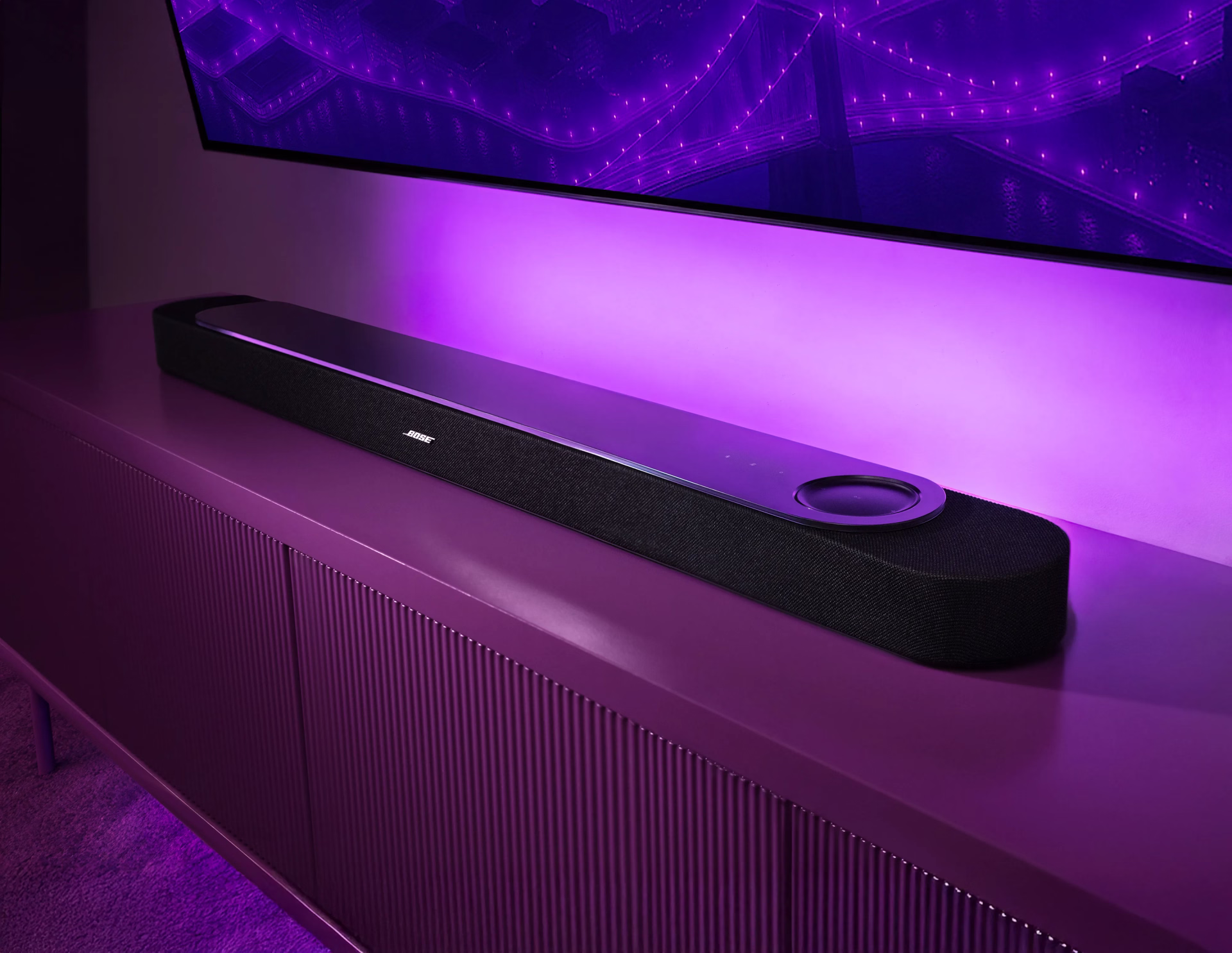 Lifestyle Ultra Soundbar displayed beneath a TV with ambient lighting, highlighting its premium design, integrated controls, and immersive home theater performance in a modern entertainment setup.
