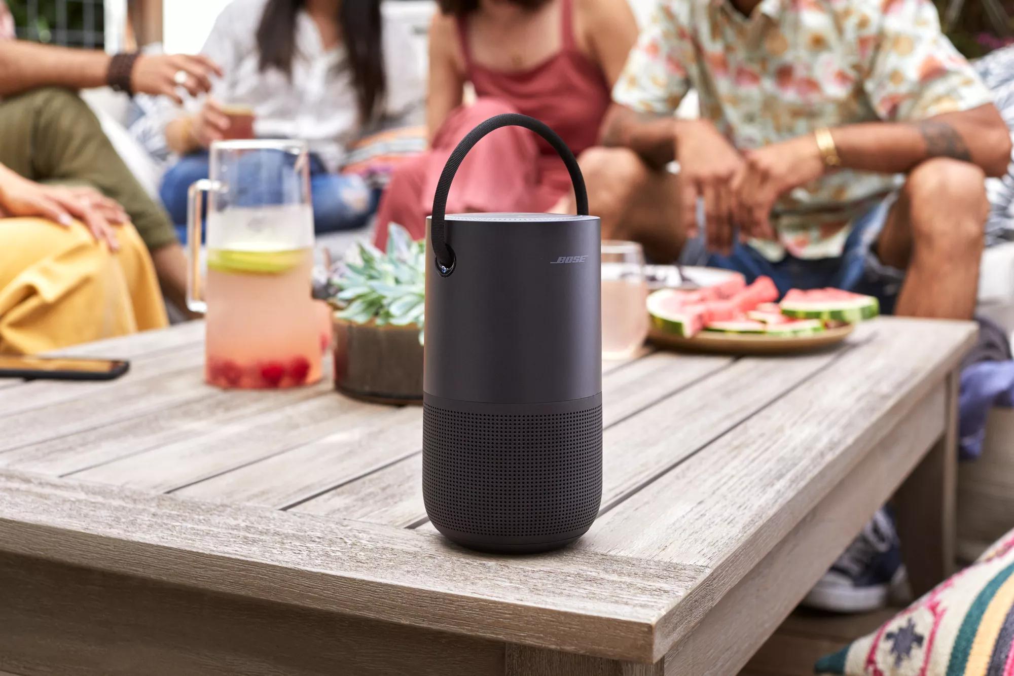 Group of friends eating and drinking outside while listening to music on Bose Portable Smart Speaker