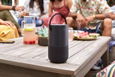 Group of friends eating and drinking outside while listening to music on Bose Portable Smart Speaker