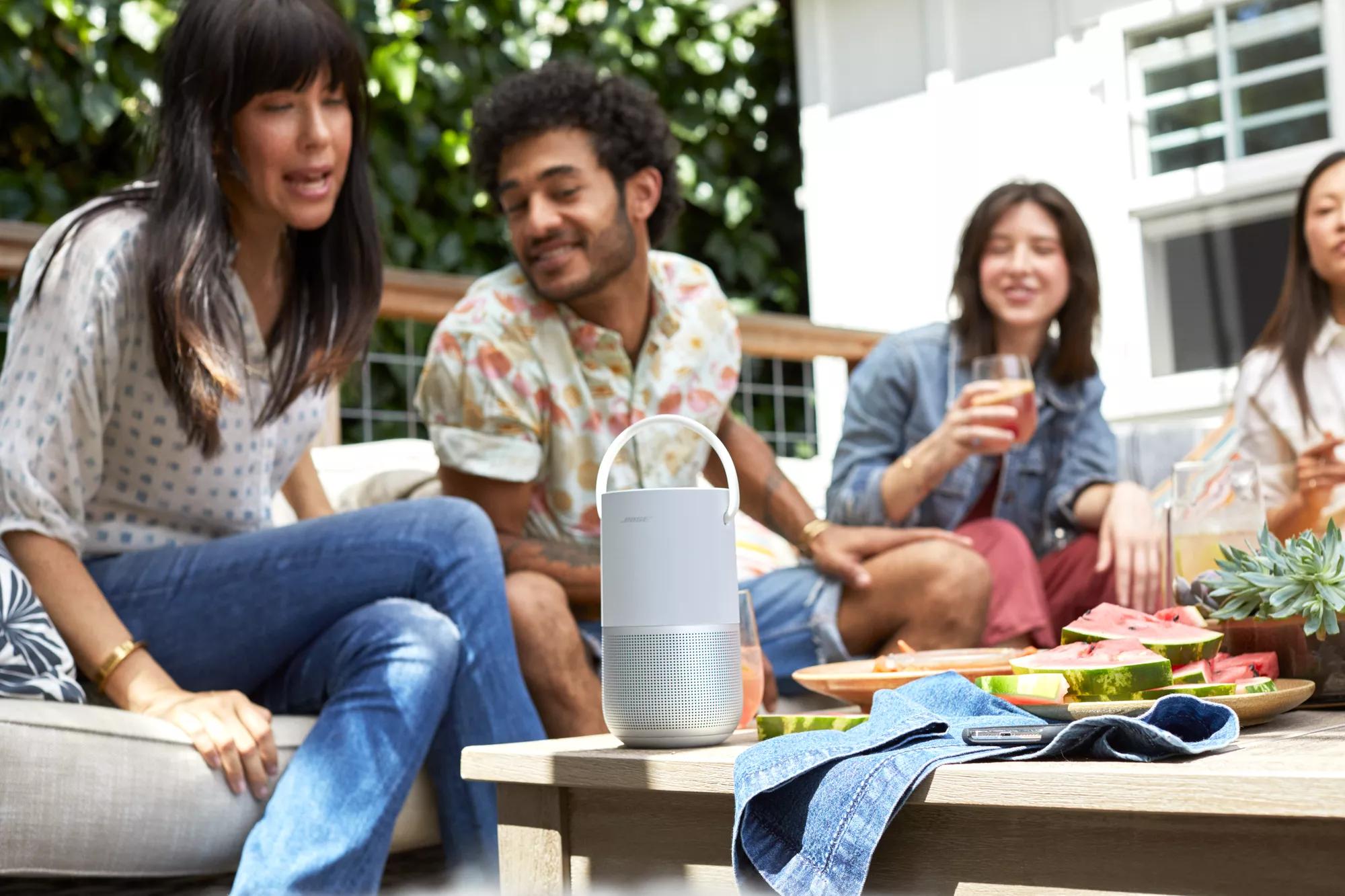 Friends eating and drinking outside while using the Voice Assistants in Bose Portable Smart Speaker
