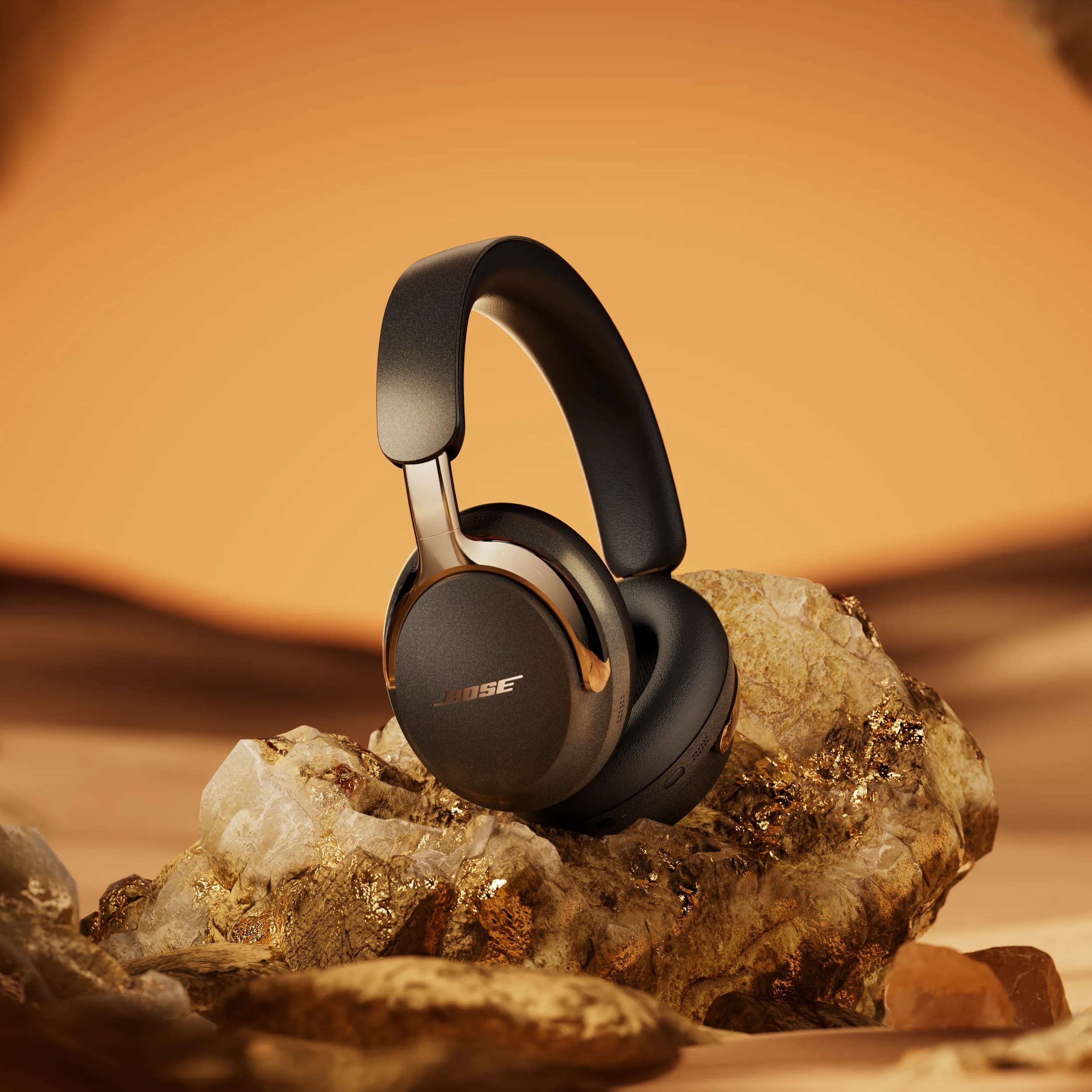 Black QuietComfort Ultra Headphones LE (2nd Gen) standing on rocks in a desert environment.