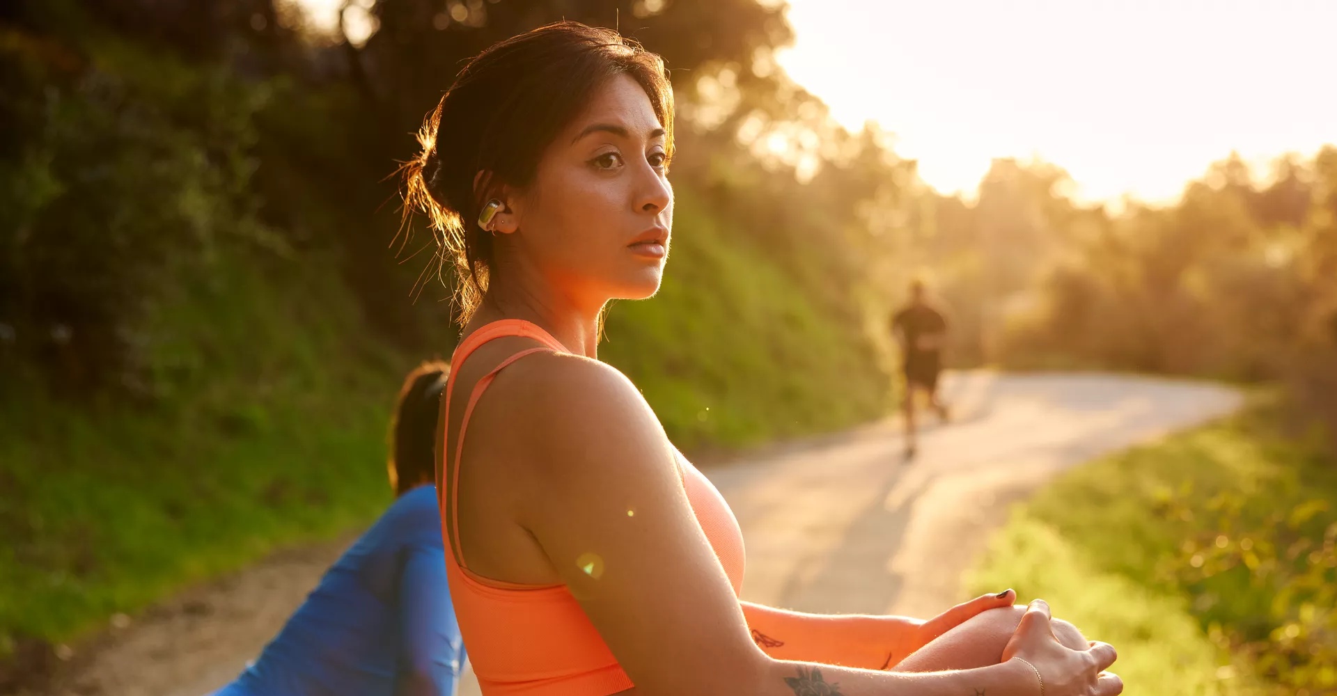 Woman stretching before a run wearing Bose Ultra Open Earbuds