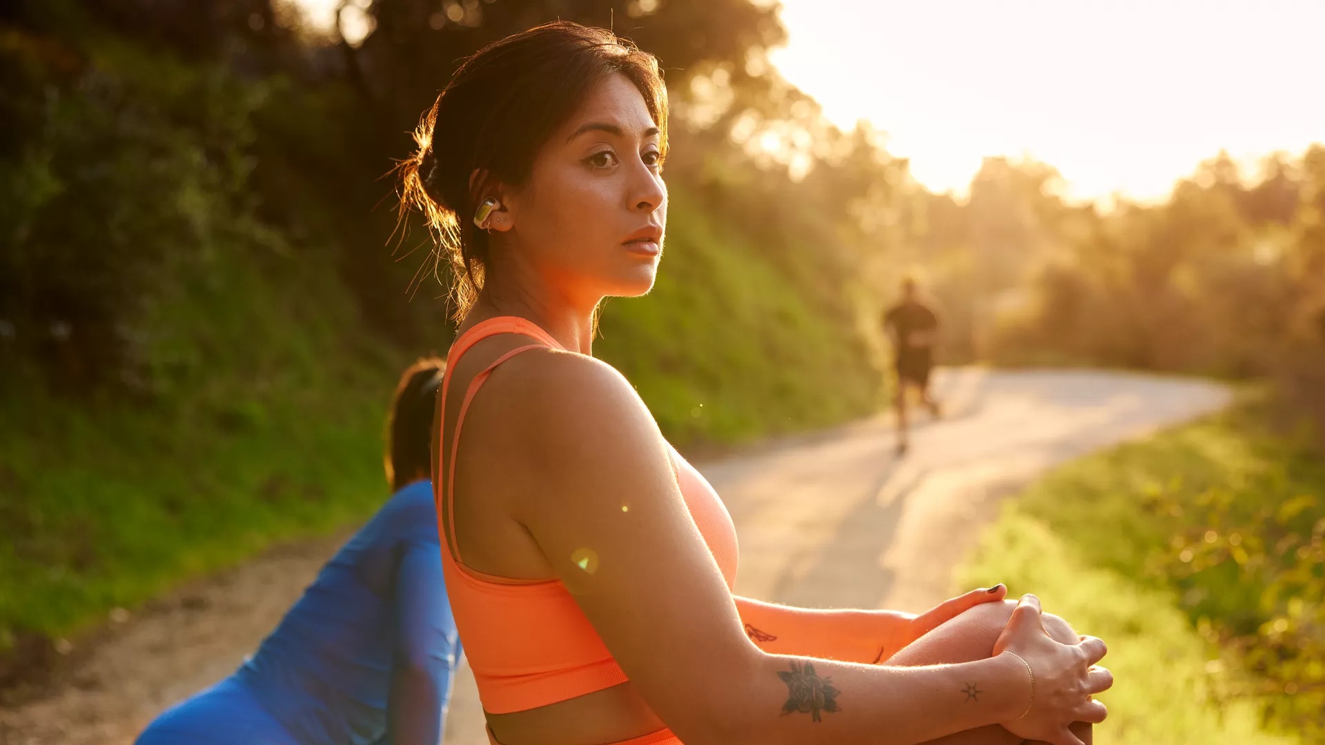 Woman stretching before a run wearing Bose Ultra Open Earbuds