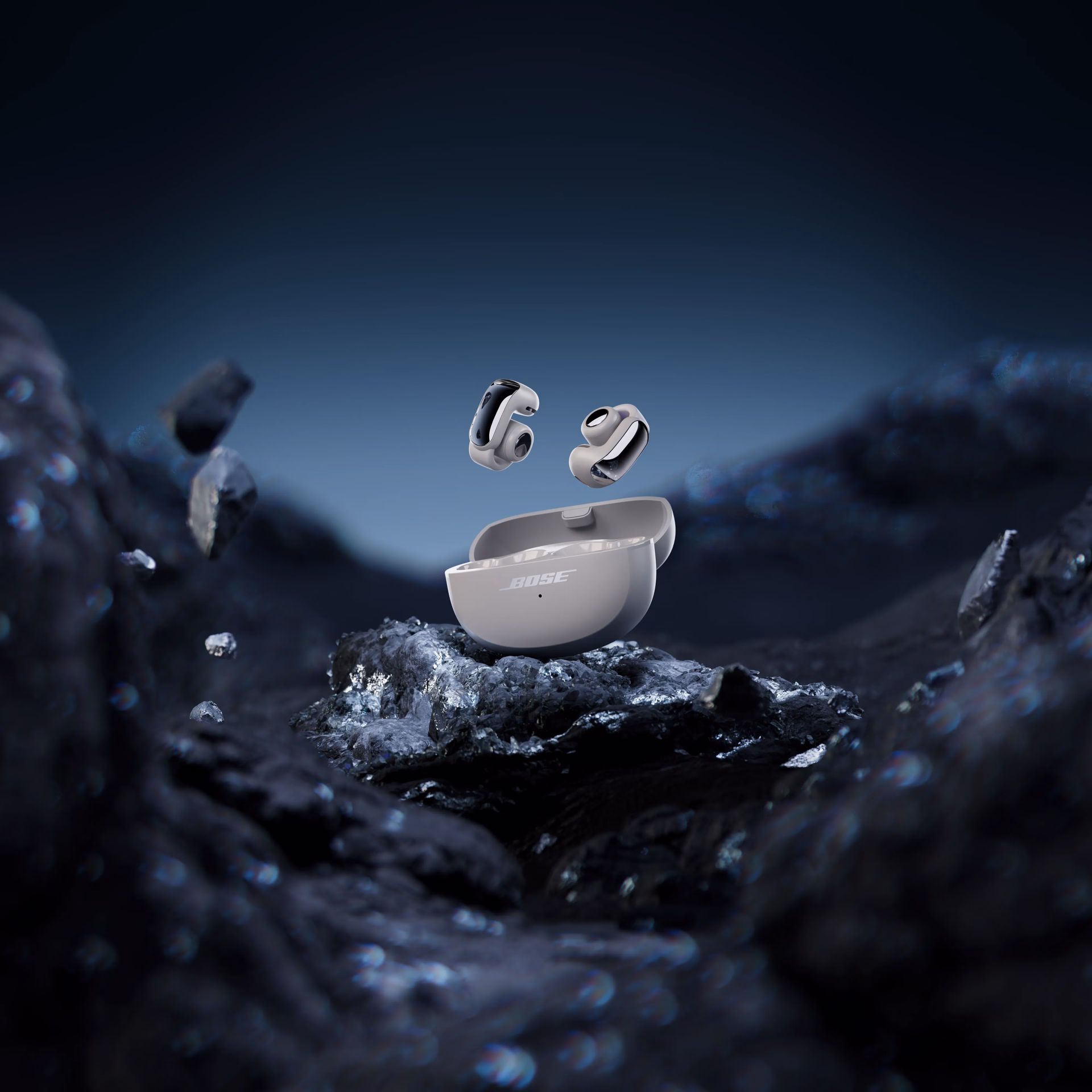 White Ultra Open Earbuds LE standing on a natural rock.