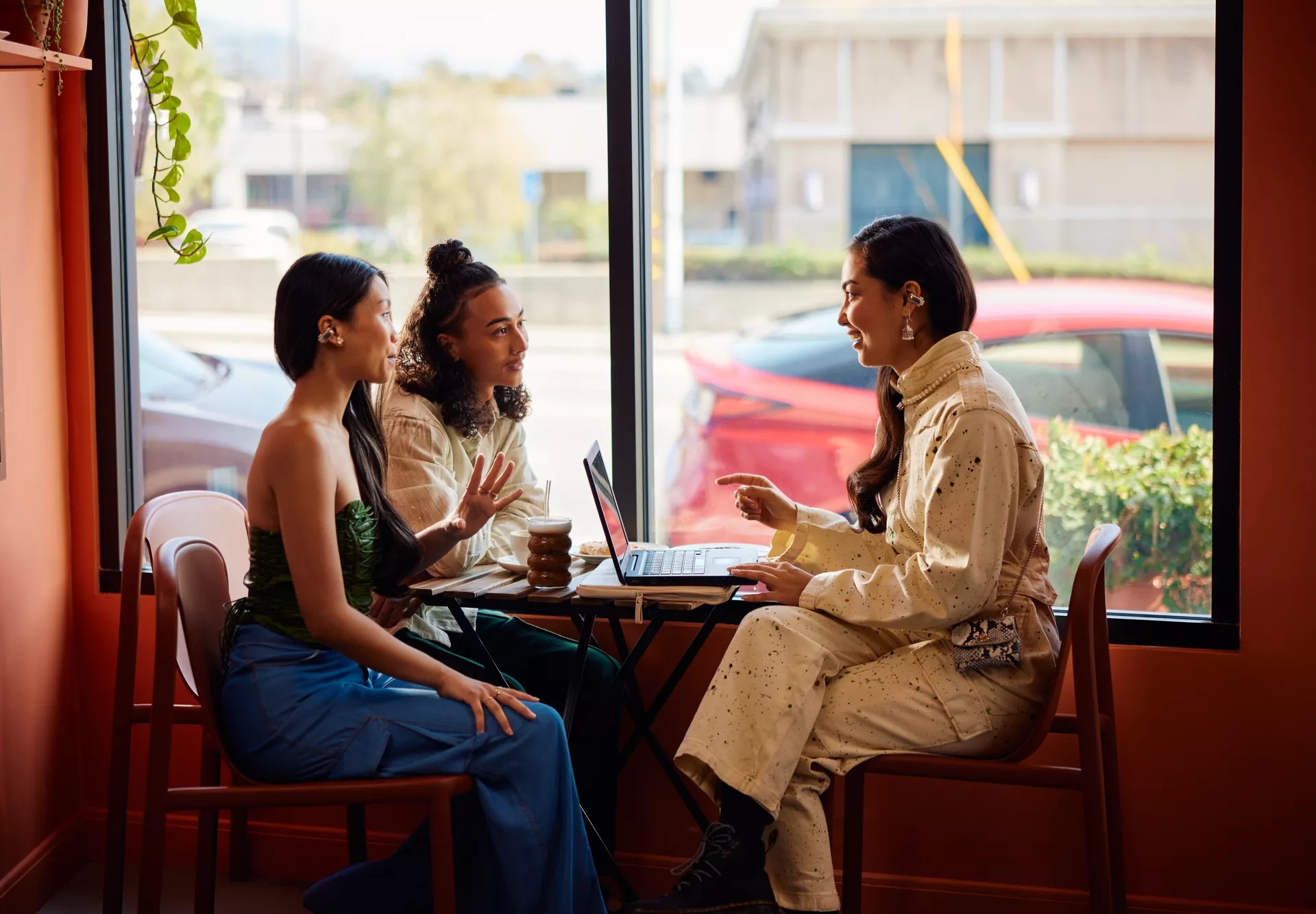 Group in coffee shop working on project together while wearing Bose Ultra Open Earbuds