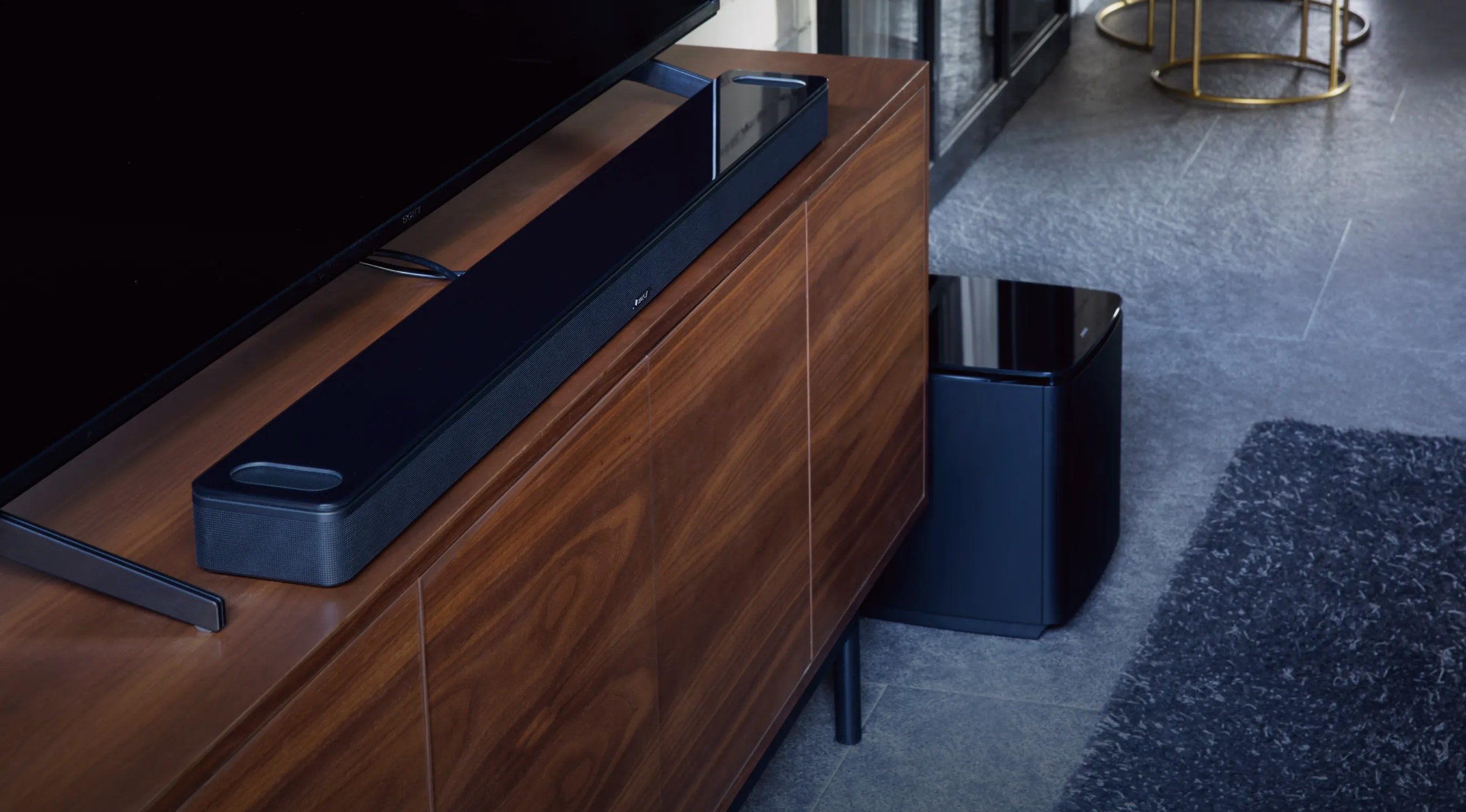 Bose soundbar on a TV console and a Bose subwoofer on the floor next to the console.