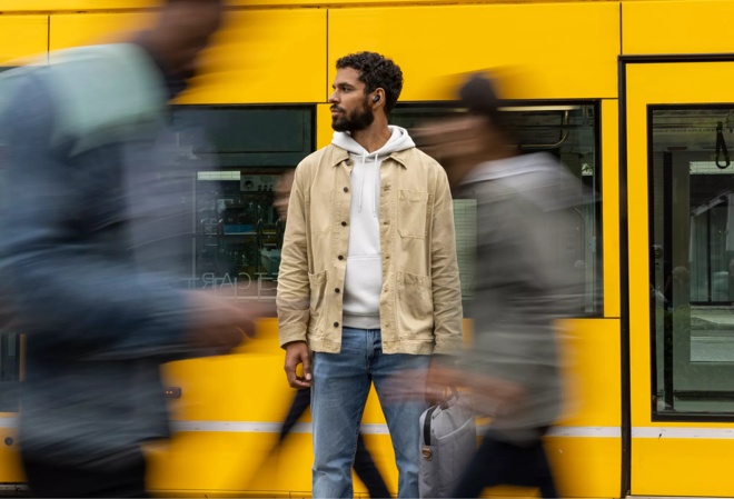 Homme portant des écouteurs Bose QuietComfort II dans une rue en ville