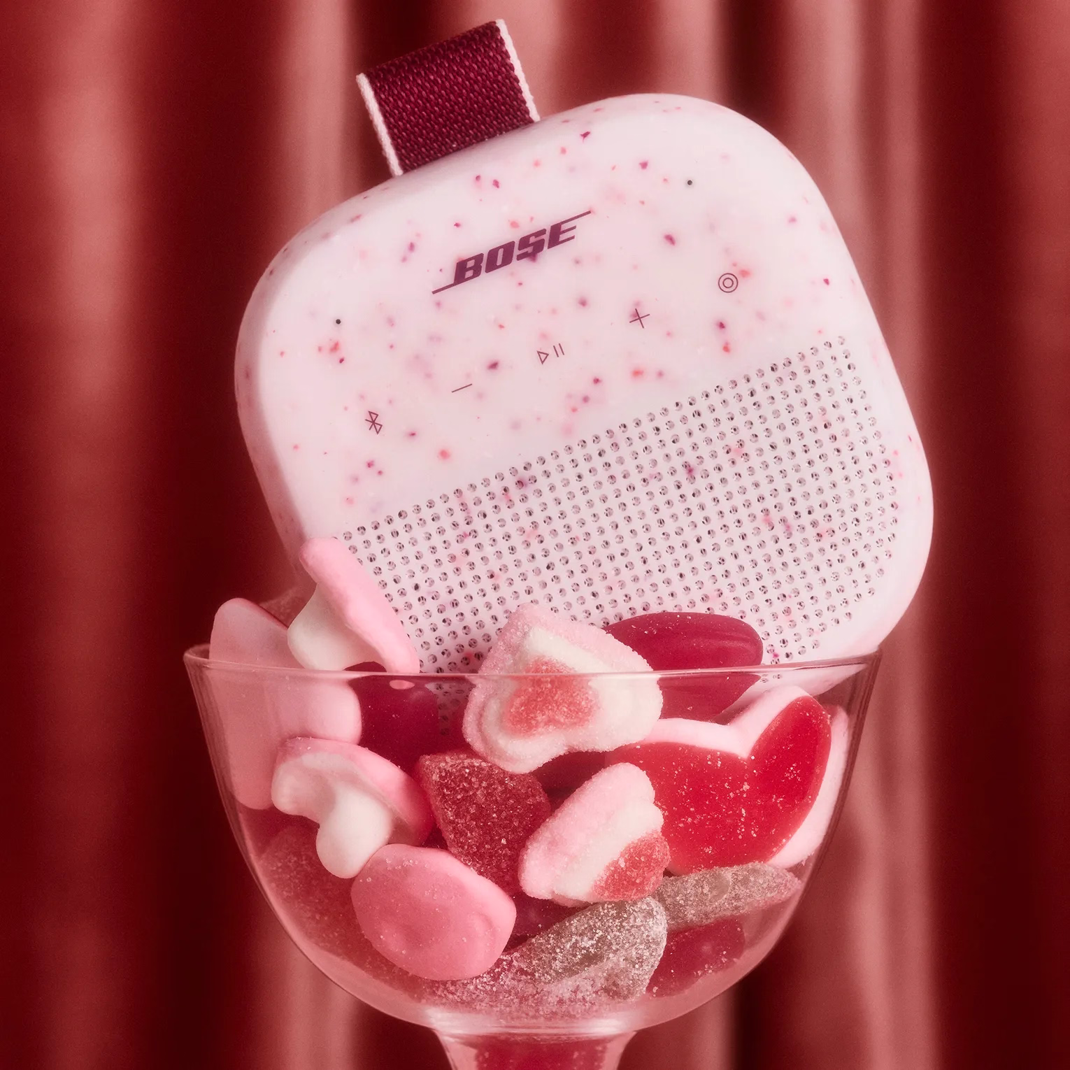 Bose SoundLink Micro Portable Speaker (2nd Gen) in Petal Pink and an assortment of BonBon candy in a wine glass.