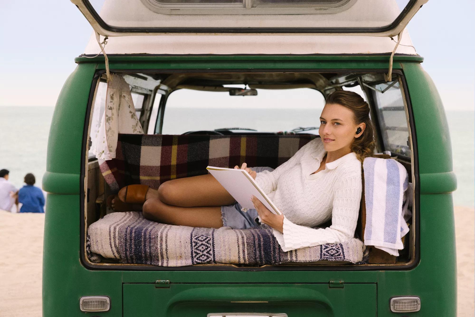 Woman wearing Bose QuietComfort Earbuds II relaxing in the back of a pickup truck