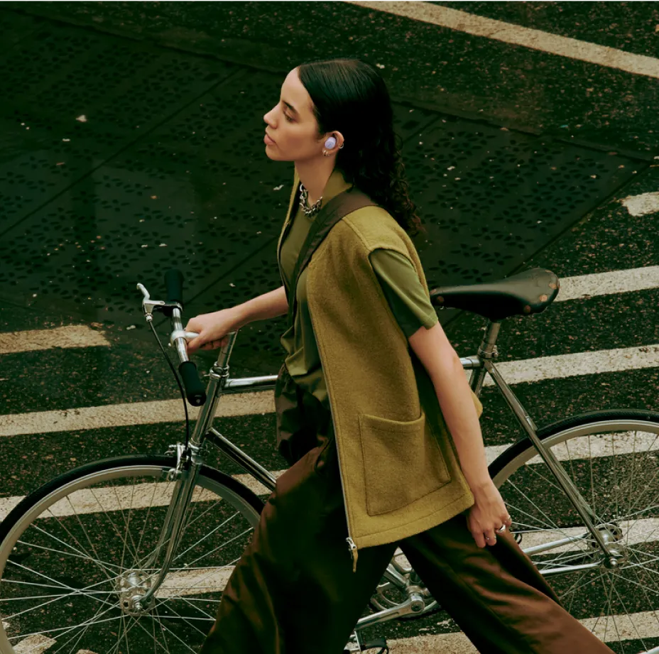 Woman walking her bike wearing Bose QuietComfort Earbuds.