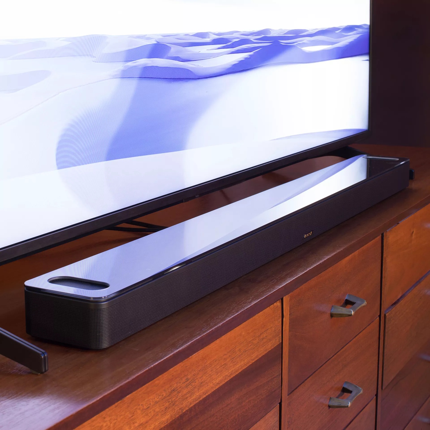 Black Smart Ultra Soundbar standing in a wood tv cabinet