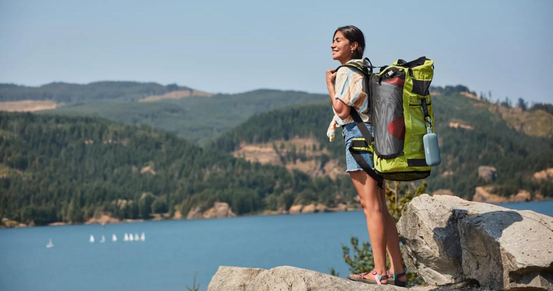 Woman hiking with a Bose Soundlink Flex Bluetooth Speaker attached to her backpack