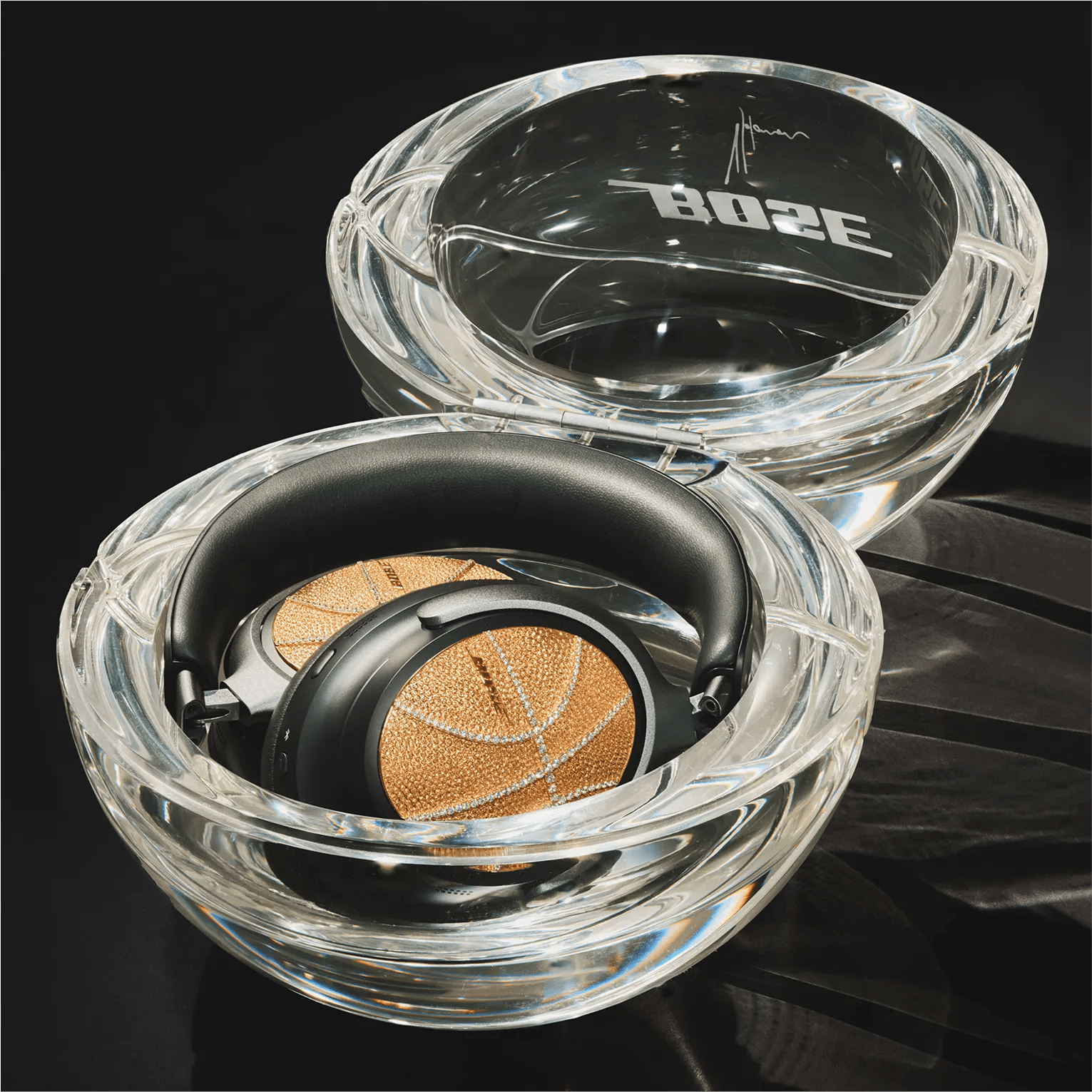 Designed by Victor Solomon, Bose QuietComfort Ultra Headphones in their clear case shaped like a basketball.