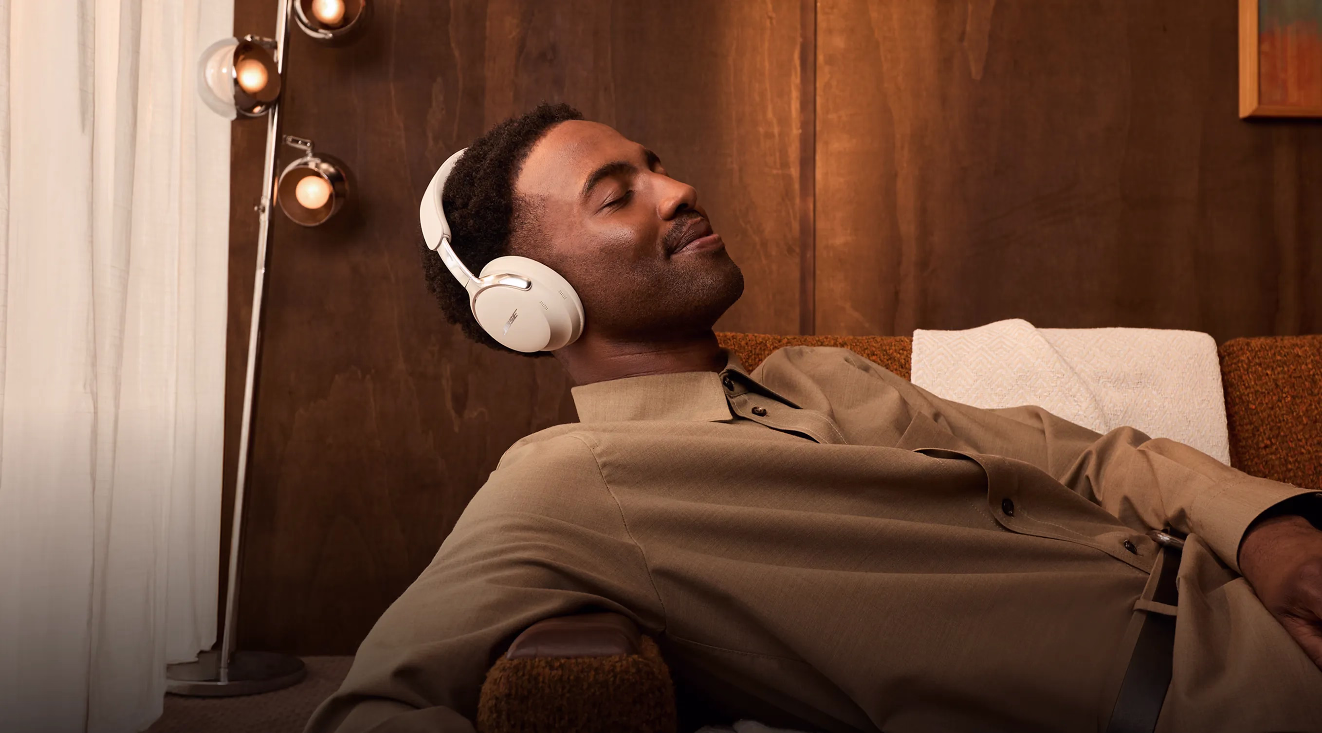 A dad relaxing on a couch with his eyes closed wearing Bose QuietComfort Ultra Headphones (2nd Gen).