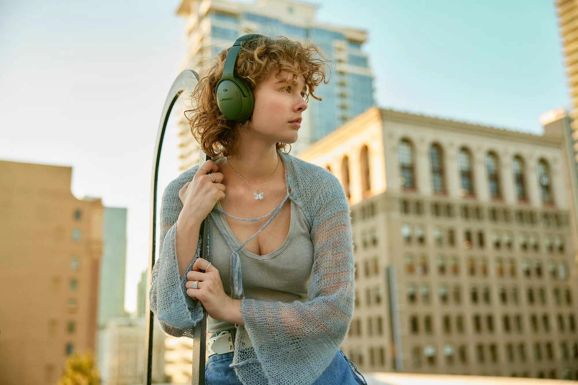 Woman sitting outside wearing Cypress Green QuietComfort Headphones