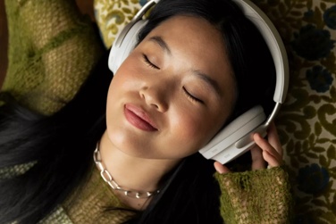 Woman laying down listening to music with QuietComfort Ultra Headphones
