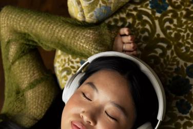 Woman laying down listening to music with QuietComfort Ultra Headphones