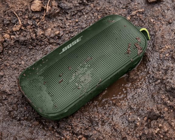 Cypress Green SoundLink Flex Bluetooth Speaker on the ground with water and mud on it