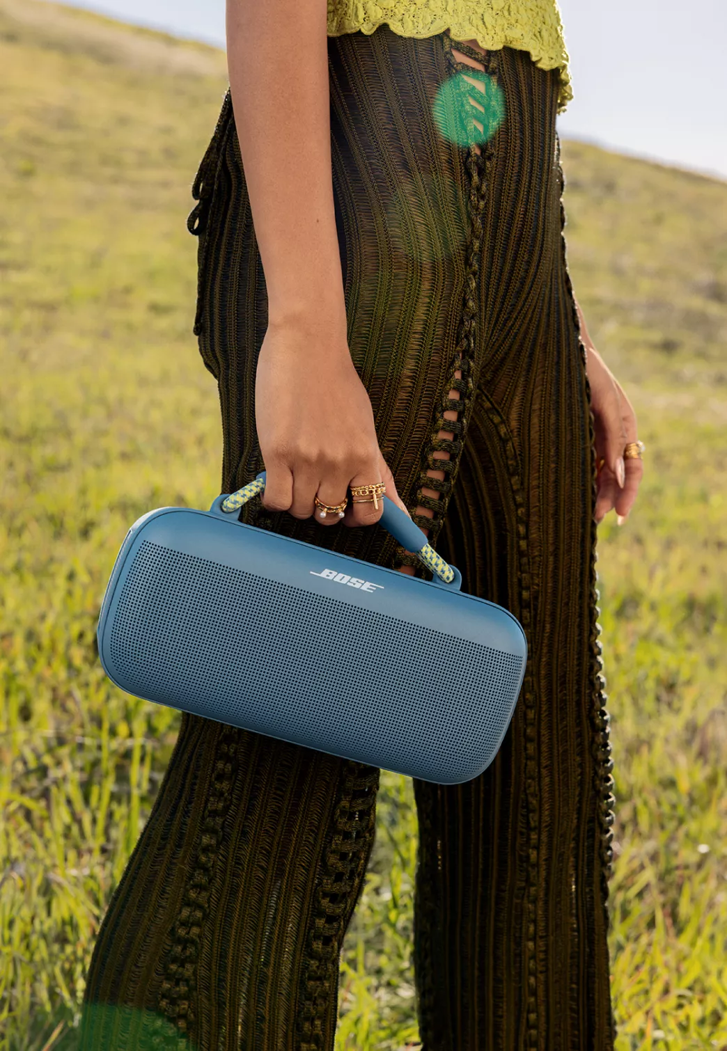 Femme portant l’enceinte portative Bose SoundLink Max avec une poignée en corde bleu brunante/hyper citron