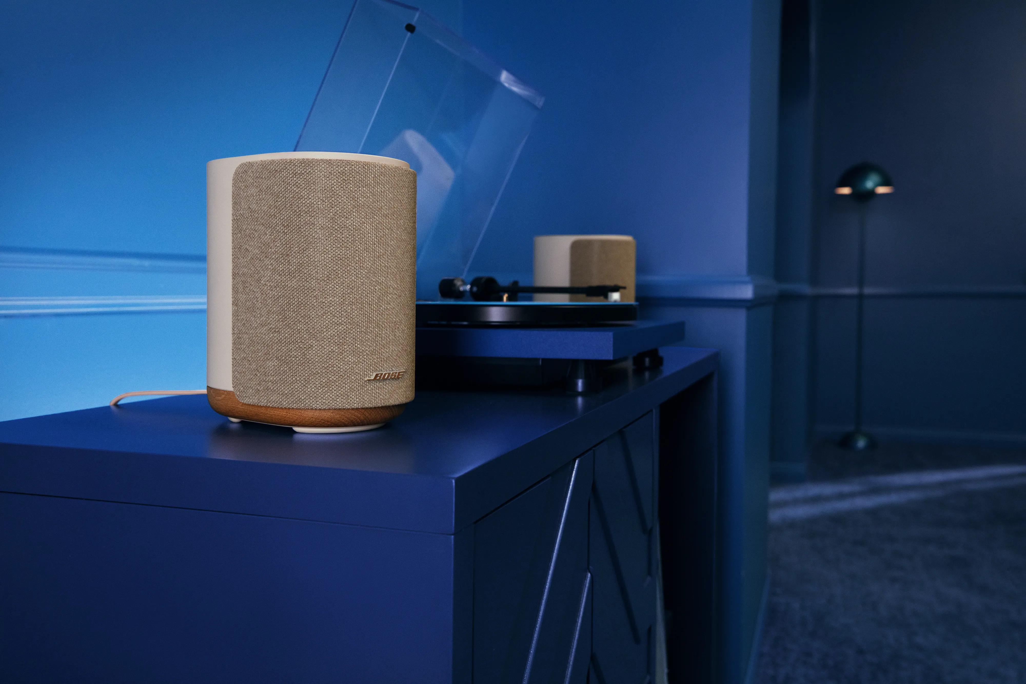 Lifestyle Ultra Speaker placed on a modern media console beside a vinyl record player in a softly lit room.